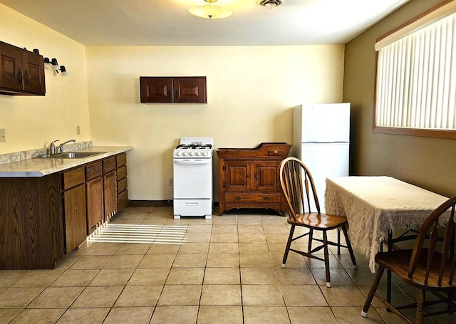 kitchen featuring light countertops, white appliances, light tile patterned flooring, and a sink