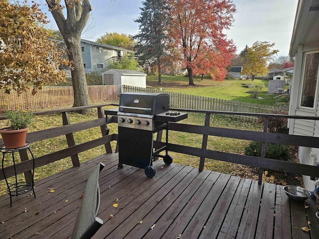 deck featuring a fenced backyard, a grill, a storage shed, and a lawn