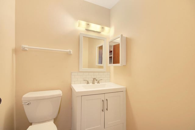 half bathroom featuring vanity, backsplash, and toilet