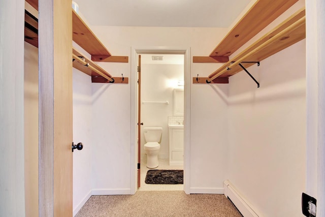 spacious closet featuring carpet, visible vents, a sink, and a baseboard radiator