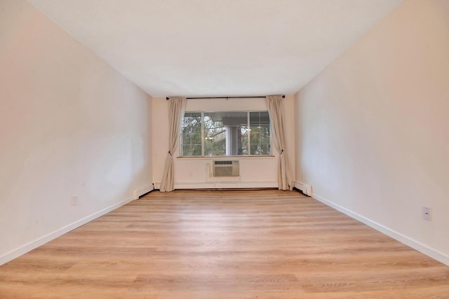 spare room featuring a baseboard heating unit, a wall mounted air conditioner, baseboards, and wood finished floors