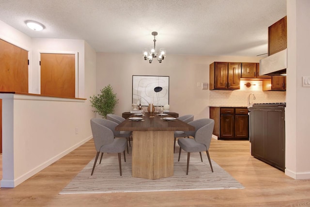 dining space featuring a chandelier, a textured ceiling, light wood-type flooring, and baseboards