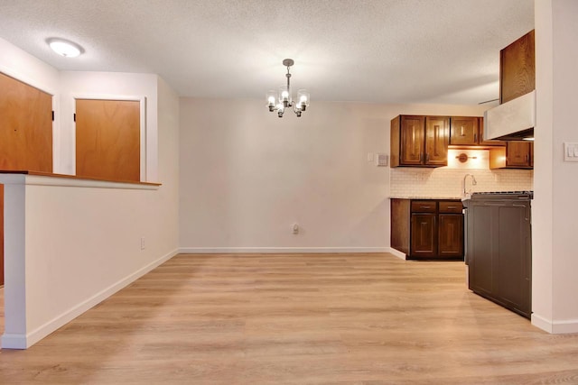 kitchen featuring light wood-style floors, baseboards, decorative backsplash, and a textured ceiling