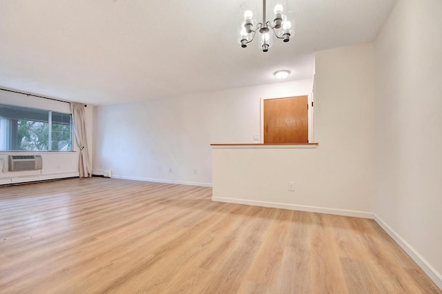 unfurnished room with light wood finished floors, baseboards, an inviting chandelier, a baseboard heating unit, and a wall mounted AC