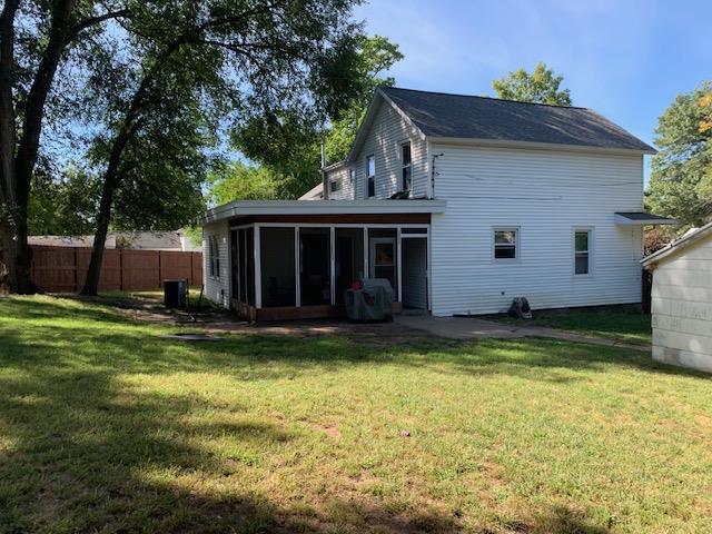 back of property with fence, a lawn, and a sunroom