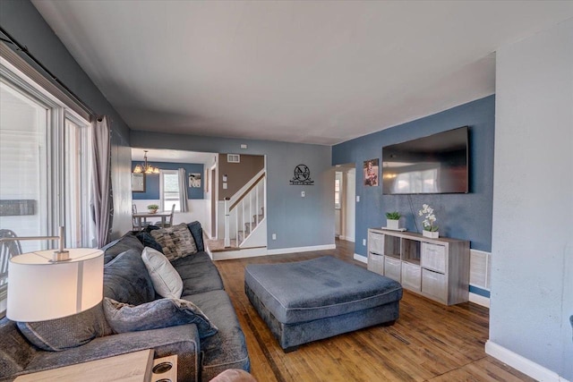 living room with stairway, wood finished floors, visible vents, baseboards, and a notable chandelier