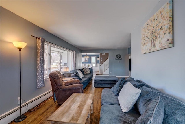 living room with baseboards, stairs, baseboard heating, wood finished floors, and a notable chandelier