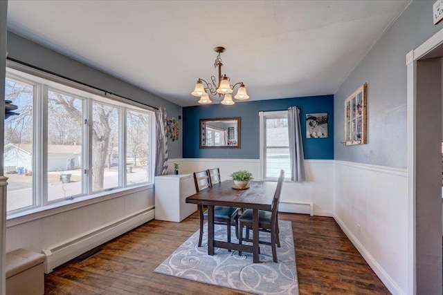 dining area with wood finished floors, a wainscoted wall, a chandelier, and a baseboard radiator