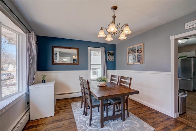 dining space with wood finished floors, baseboard heating, and wainscoting