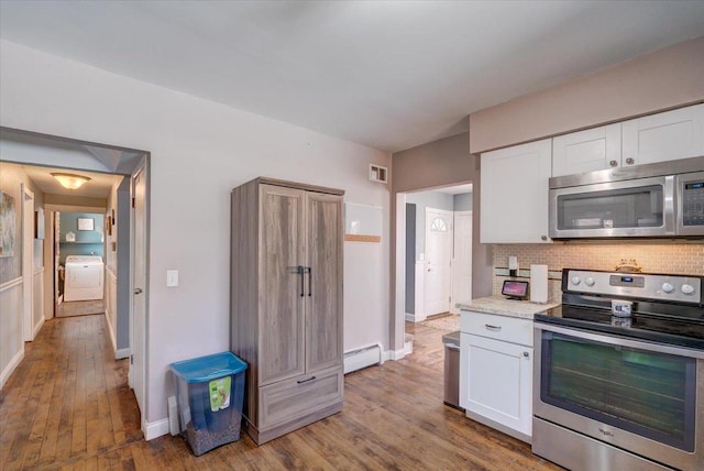 kitchen featuring washer / clothes dryer, wood finished floors, white cabinetry, appliances with stainless steel finishes, and baseboard heating