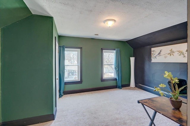 interior space featuring carpet flooring, a textured ceiling, baseboards, and vaulted ceiling