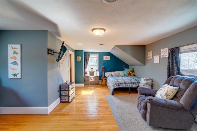 bedroom with baseboards, light wood-type flooring, and a textured ceiling