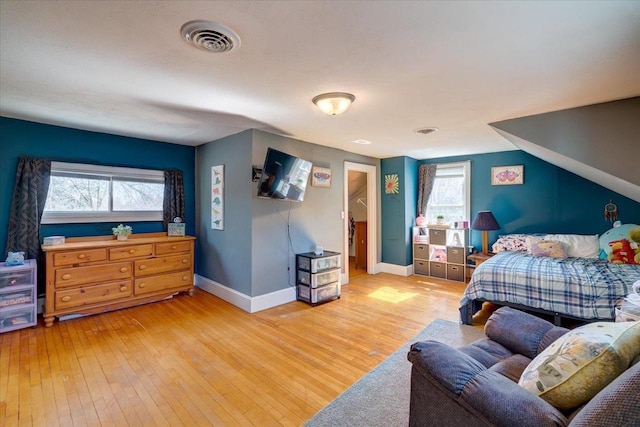 bedroom with hardwood / wood-style floors, lofted ceiling, baseboards, and visible vents