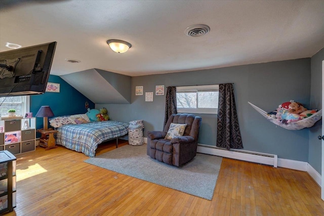 bedroom with vaulted ceiling, wood-type flooring, visible vents, and baseboard heating