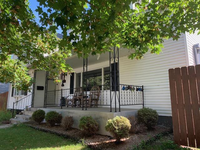 rear view of property with covered porch and fence