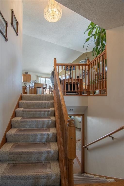 stairs with lofted ceiling, a notable chandelier, a textured ceiling, and baseboards