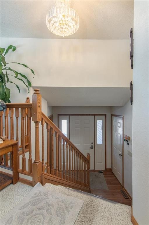 entryway featuring stairs, baseboards, wood finished floors, and a notable chandelier