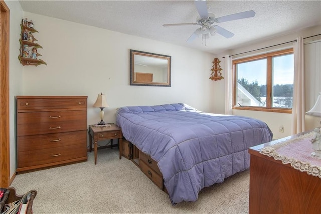 bedroom featuring a ceiling fan, a textured ceiling, and light colored carpet