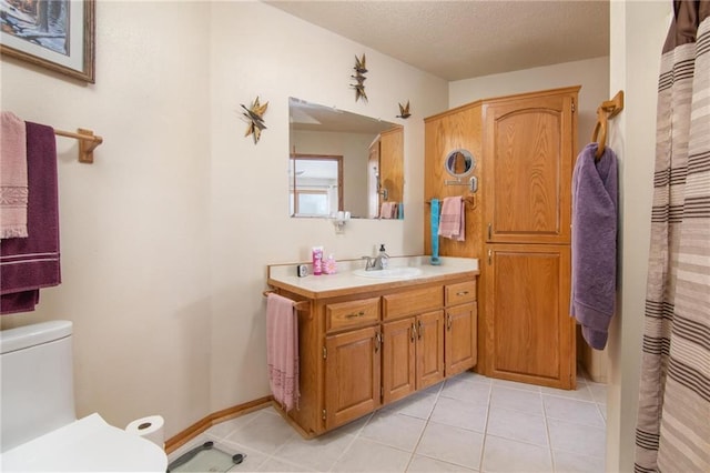 full bathroom with a textured ceiling, tile patterned flooring, toilet, vanity, and baseboards