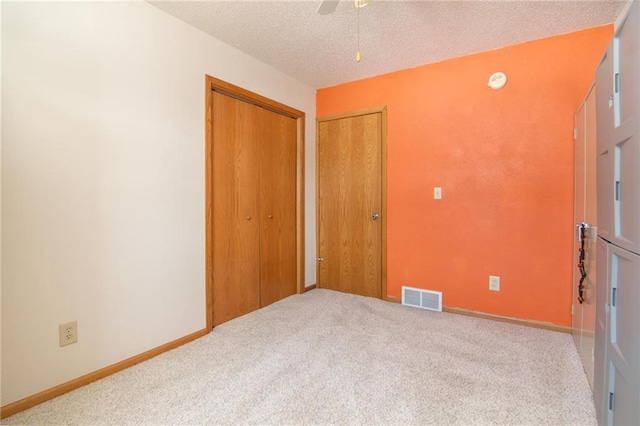 unfurnished bedroom with carpet floors, visible vents, ceiling fan, a textured ceiling, and baseboards