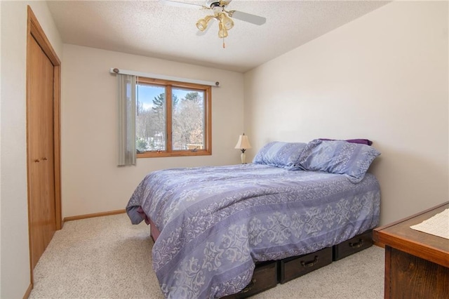 bedroom with baseboards, ceiling fan, carpet, a textured ceiling, and a closet