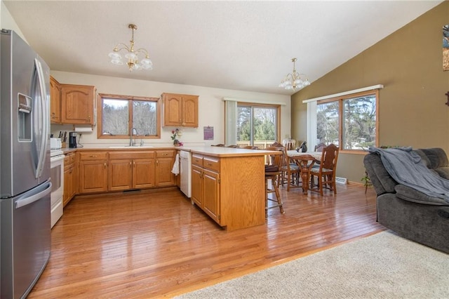 kitchen featuring an inviting chandelier, open floor plan, a sink, white appliances, and a peninsula