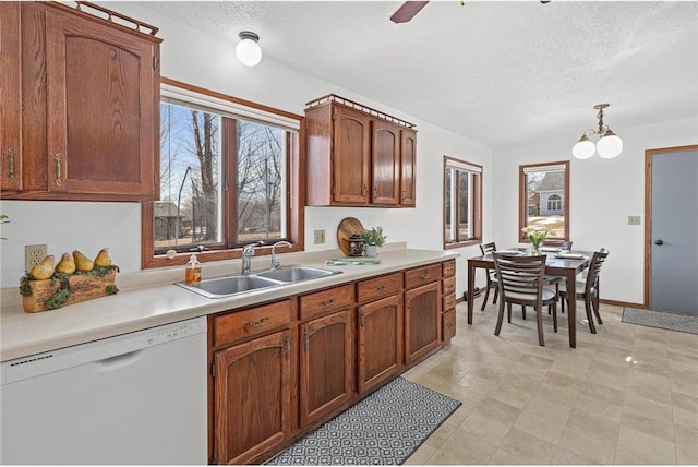 kitchen with a sink, a textured ceiling, dishwasher, and light countertops