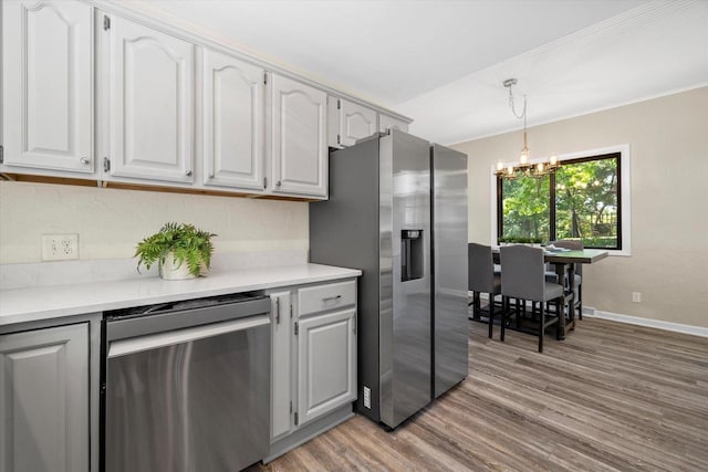 kitchen with stainless steel appliances, light wood-style floors, light countertops, decorative light fixtures, and an inviting chandelier