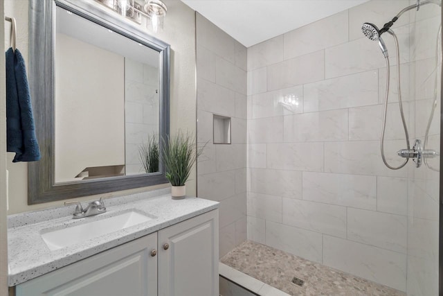 bathroom featuring tiled shower and vanity