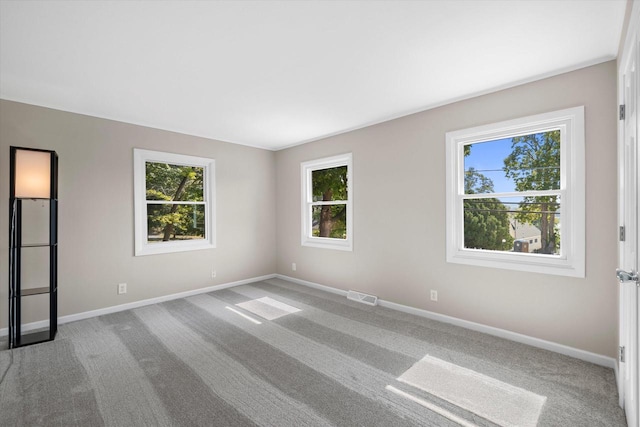 empty room featuring carpet floors, visible vents, and baseboards