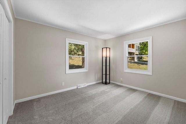 unfurnished room featuring baseboards, visible vents, crown molding, and carpet flooring