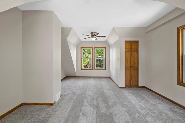 bonus room with light carpet, vaulted ceiling, baseboards, and ceiling fan