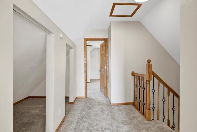 hallway featuring lofted ceiling, carpet, an upstairs landing, and baseboards