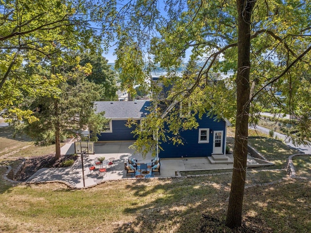 rear view of house featuring a yard, roof with shingles, and a patio