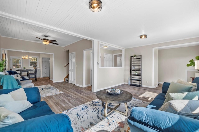 living room featuring an inviting chandelier, baseboards, stairway, and wood finished floors