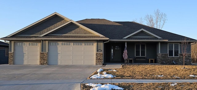 craftsman-style house with a garage, stone siding, covered porch, and driveway