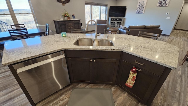 kitchen featuring light wood-style flooring, open floor plan, dark brown cabinets, stainless steel dishwasher, and a sink