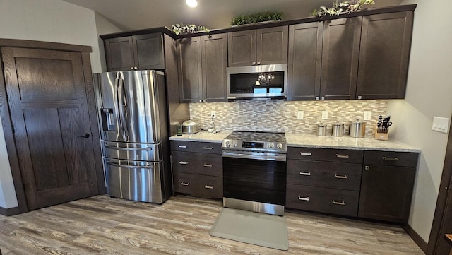 kitchen featuring light stone counters, dark brown cabinetry, stainless steel appliances, light wood-type flooring, and tasteful backsplash