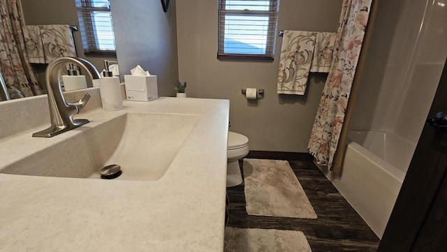 bathroom with a healthy amount of sunlight, baseboards, toilet, and a sink