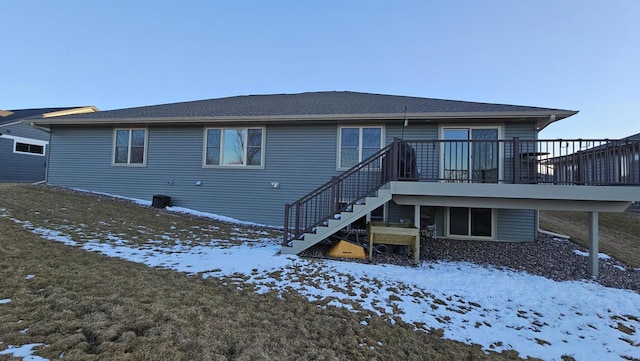 snow covered back of property featuring stairs and a deck