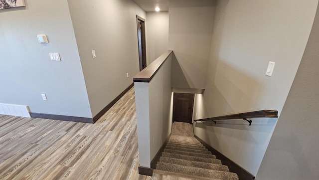 staircase with wood finished floors, visible vents, and baseboards