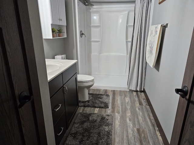 full bathroom featuring toilet, a stall shower, wood finished floors, and vanity