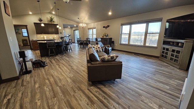 living room featuring high vaulted ceiling, an inviting chandelier, baseboards, and dark wood-type flooring