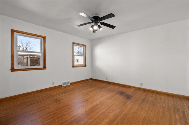 unfurnished room with baseboards, light wood-type flooring, visible vents, and a ceiling fan