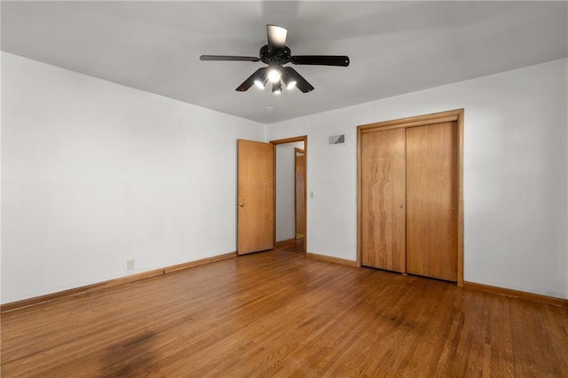 unfurnished bedroom with a closet, ceiling fan, baseboards, and wood finished floors