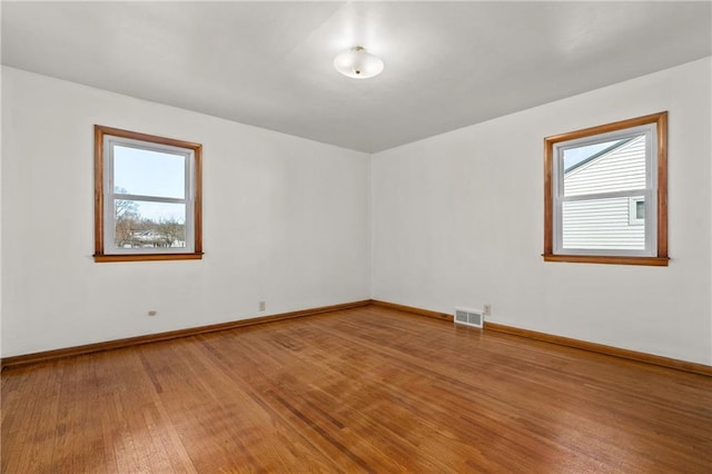 spare room featuring visible vents, baseboards, and wood finished floors