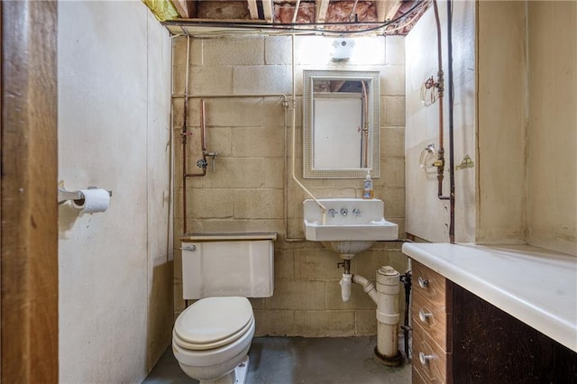 half bath featuring toilet, concrete floors, a sink, and concrete block wall