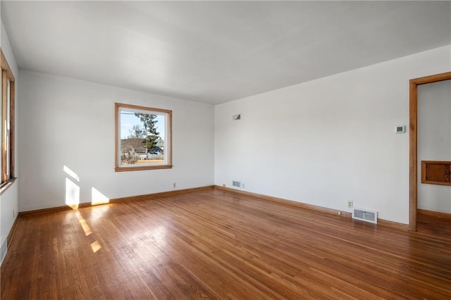 unfurnished room with wood finished floors, visible vents, and baseboards