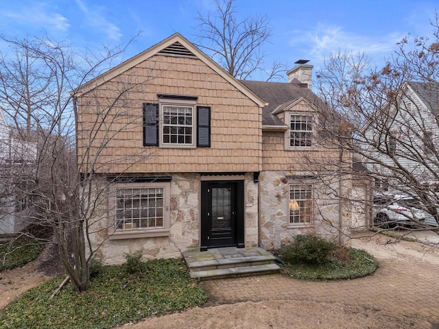 view of front facade featuring a chimney and a shingled roof