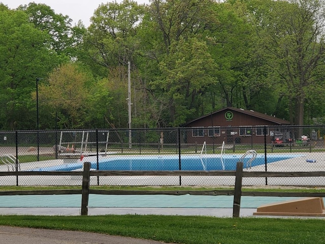 view of pool with community basketball court, fence, and a forest view